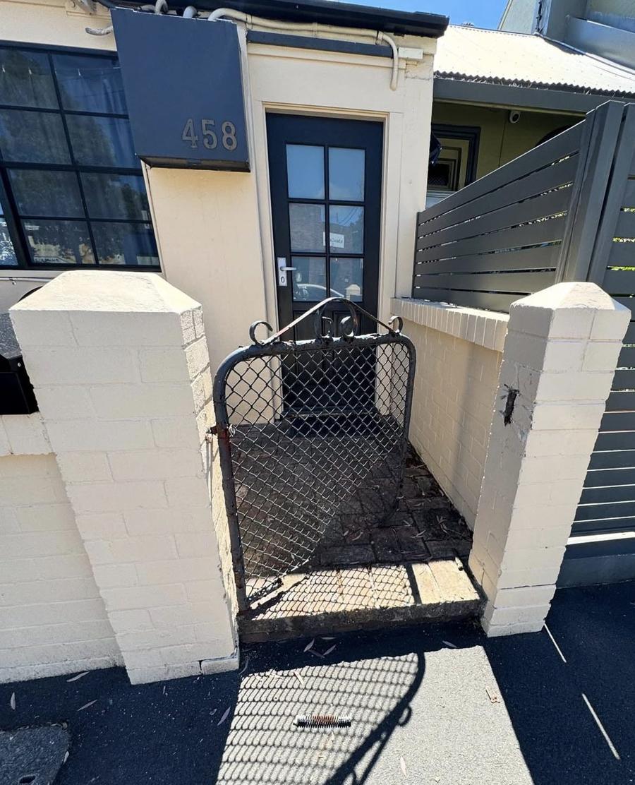 Old rusted wire gate between rendered brick pillars