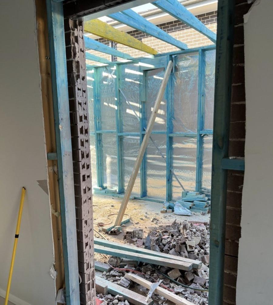 New opening cut through the brick wall with timber framing visible beyond