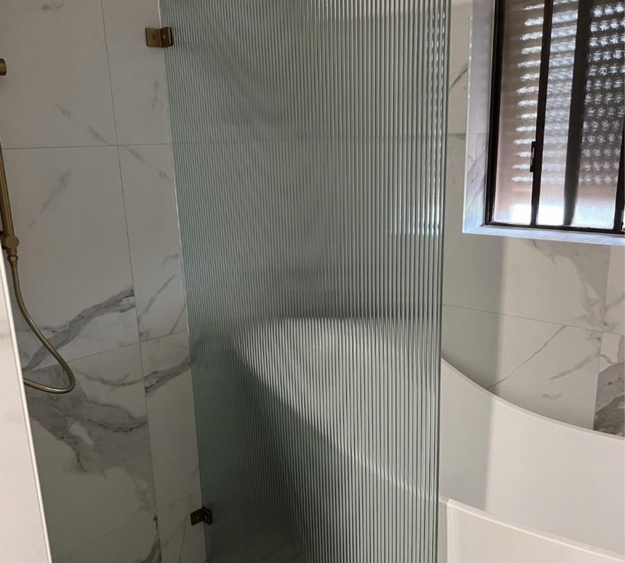 Fluted glass fixed shower panel with gold brackets